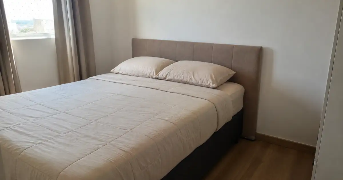 cabeceira estofada apoiada no piso atras de cama box em quarto alugado pequeno