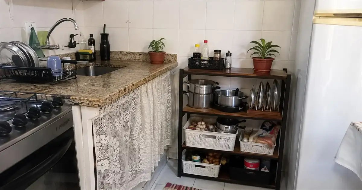 estante baixa com panelas tampas e mantimentos em cestos em cozinha alugada pequena