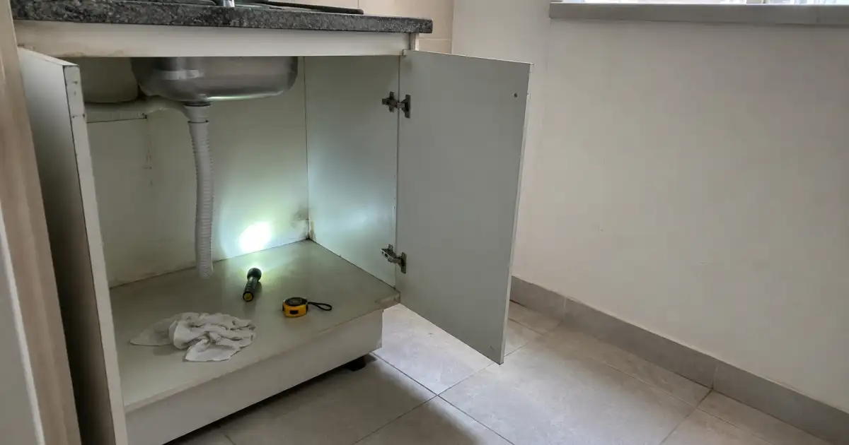 inspecao de rodape e armario sob pia durante visita de apartamento para alugar