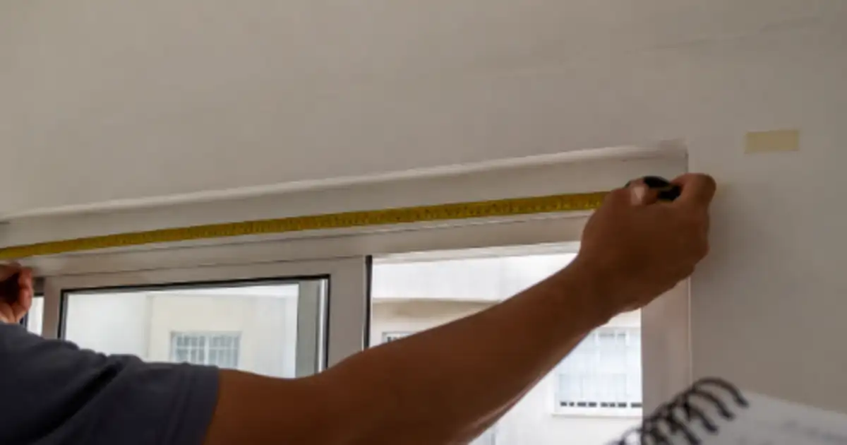 trena medindo o vao de uma janela antes de instalar cortina sem furar parede
