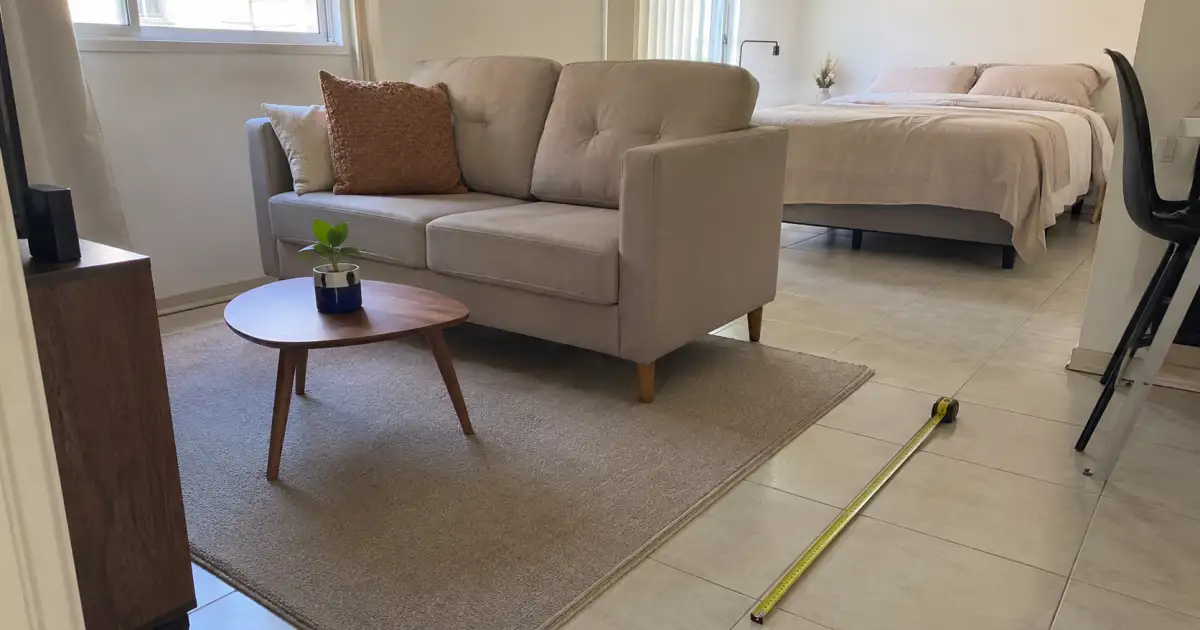 tapete de pelo baixo alinhado ao sofa e a mesa de centro em studio alugado pequeno