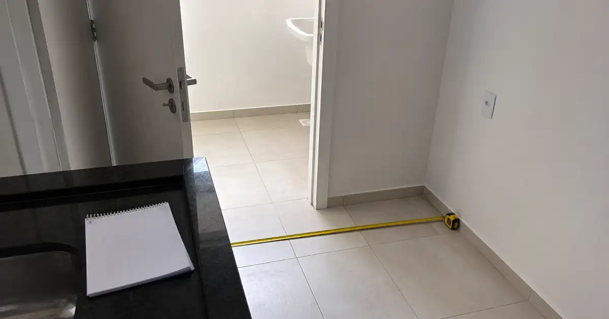 trena medindo espaco de geladeira e passagem em cozinha de apartamento vazio